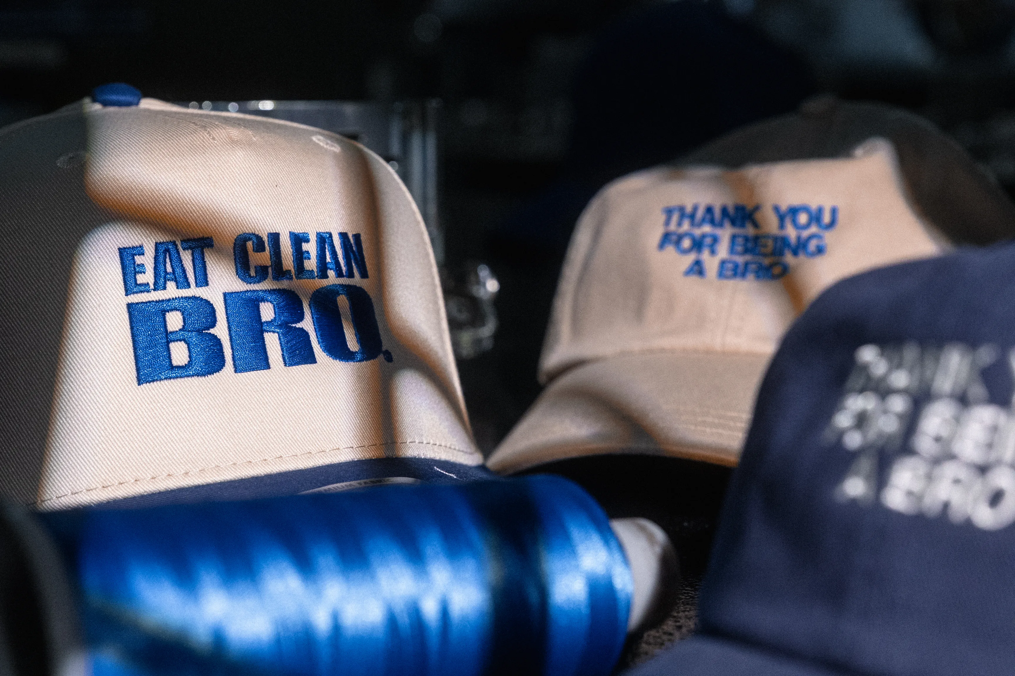 Freshly embroidered custom caps with a thread spool on the production floor at Elite Custom Apparel in Sayreville, New Jersey